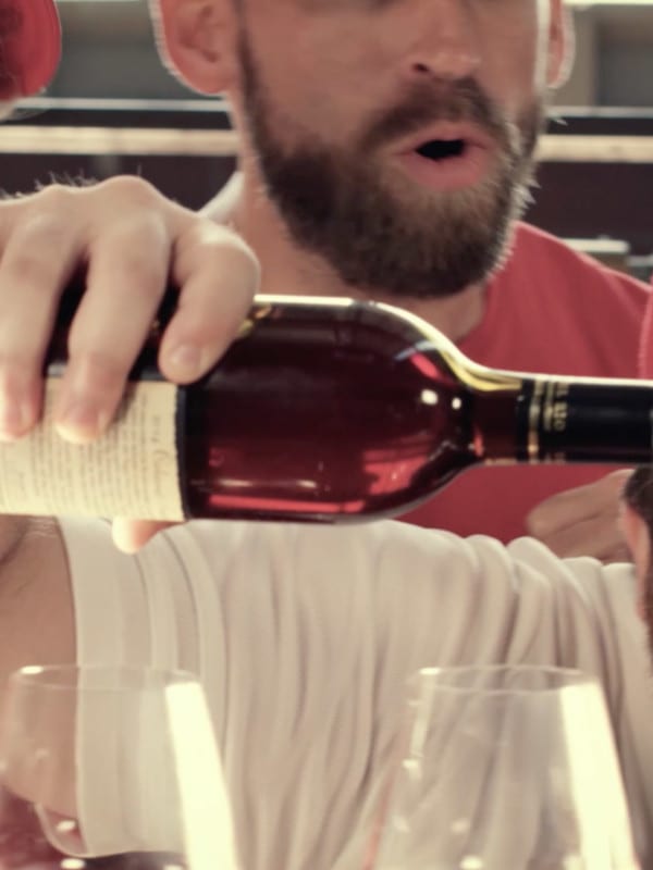 Fan in baseball gear pouring wine with friends