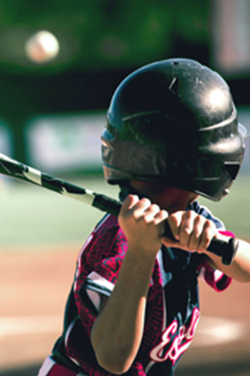 Child in baseball helmet swinging a bat